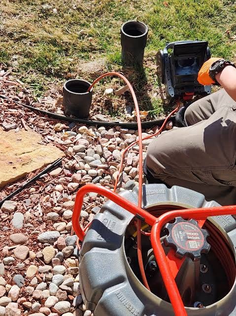 Plumbing technician using RIDGID SeeSnake color video camera and monitor for sewer pipe inspection