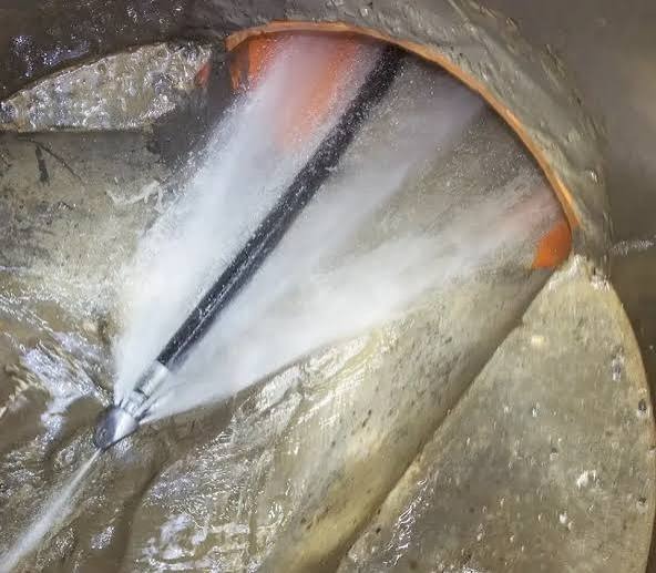 High-pressure 4,000 PSI hydro jetting nozzle blasting high velocity water jets inside a sewer pipe