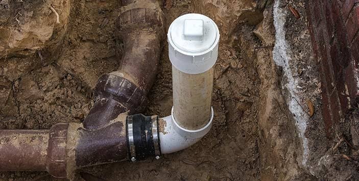 Excavated sewer pipe line repair with new PVC cleanout riser fitting installed underground